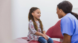 A cute little girl smiles as a caring dental assistant or hygienist eases her concerns about her dental appointment.