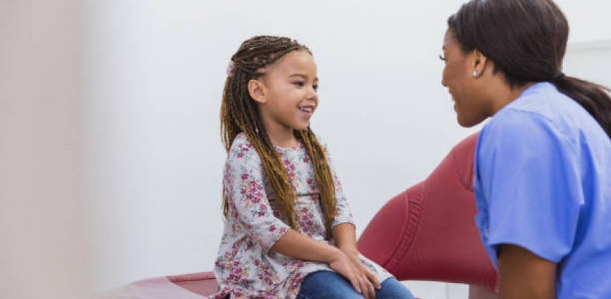 A cute little girl smiles as a caring dental assistant or hygienist eases her concerns about her dental appointment.